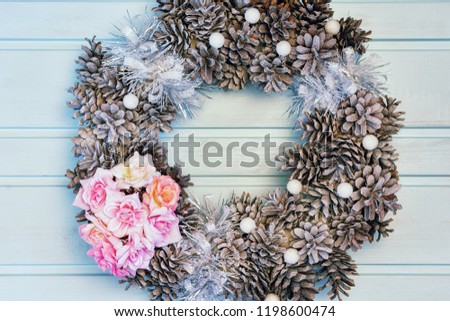 Christmas composition, frame of flowers and cones. A beautiful wreath lies on a light blue background. Holiday photography.