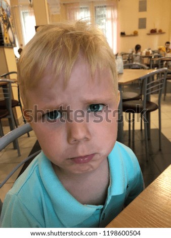 Little blond boy poses faces, showing their emotions