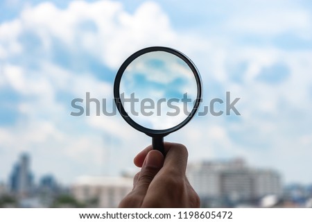 hands holding glass magnify against blue sky background. Business Explore, Searching, Discovery and Vision concepts Royalty-Free Stock Photo #1198605472