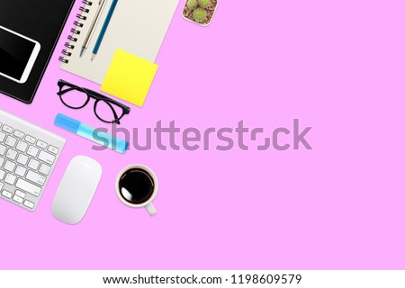 modern workspace table top view with laptop computer, coffee cup, office supplies and mobile on pink pastel background
