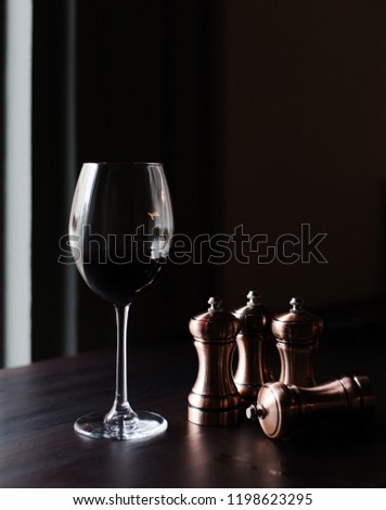 A glass of red wine and chess pieces on a dark background.