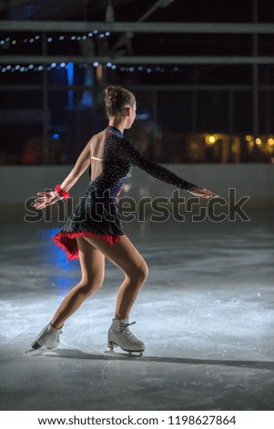 An ice skater is skating in a circle. She is enjoying her performance. 