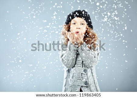 Winter portrait of cute little girl wearing warm cozy clothes studio shot with snow