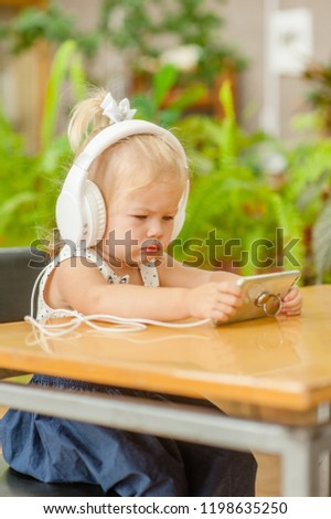 little girl watching cartoons on phone in headphones