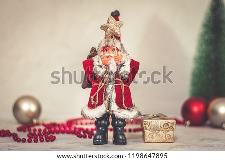 Santa Claus toy holds a staff with a star and a Christmas tree on a background of beige snowy night bokeh and blurred lights in the background Concept Happy New Year Copy space Banner, poster Flat lay
