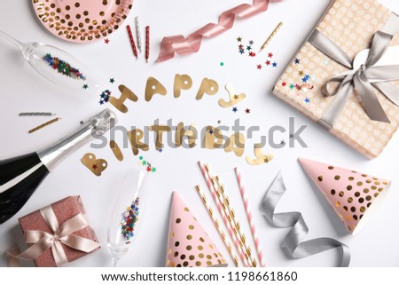 Creative flat lay composition with bottle of champagne, party accessories and words HAPPY BIRTHDAY on white background