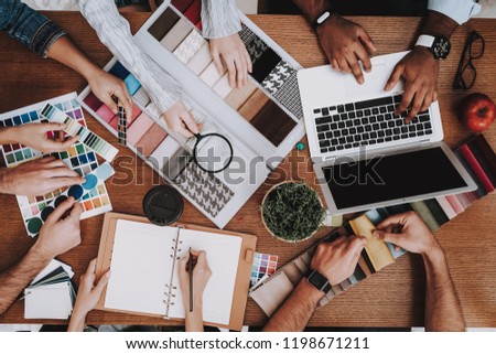 Several People. Desk. Vase and Notebook. Table. Laptop. Mouse and Pencil. Designer. Design Studio. Creative. Workplace. Samples of Color. Project. Young Specialists. Choose Colors for Design. Work.