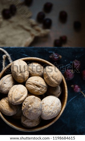 Walnuts on a black stand on the background of autumn leaves.