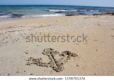 Scorcio di mare con un'ancora in primo piano disegnata sulla sabbia. Ritratto in una giornata di primavera 