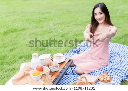 young asian female show heart sign with her hand, she relax and smile on nature background