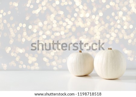 Modern autumn styled composition with white pumkins and golden sparkling bokeh lights. Halloween, Thanksgiving party concept. Festive fall design.