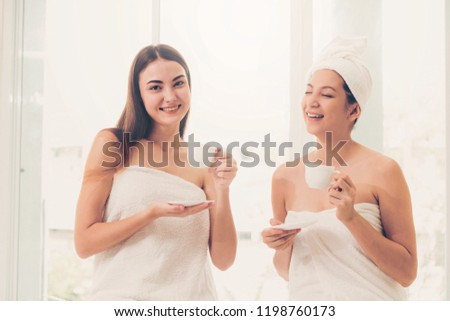 Two women drinking tea or herbal drinks while having conversation in luxury day spa. Wellness, leisure and healthcare concept.