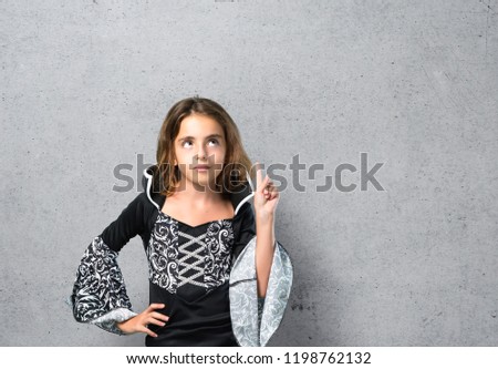 Little girl dressed as a vampire for halloween holidays standing and thinking an idea on textured background
