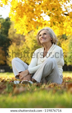 portrait of a nice old woman sitting in the autumn park