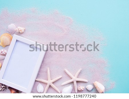 creative flat lay of beach and sea in summer holiday beach background with shells and white picture frame with copy space.