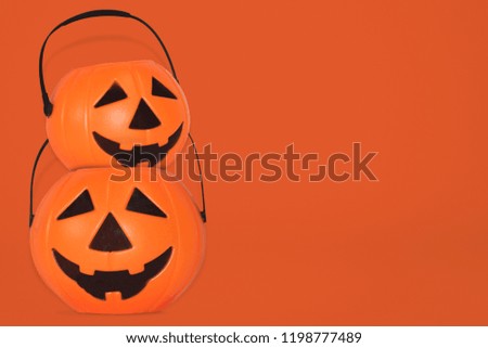 Jack O' Lantern Halloween pumpkin pail on orange background. Orange plastic Trick Or Treat candy bucket made from resin with handle.