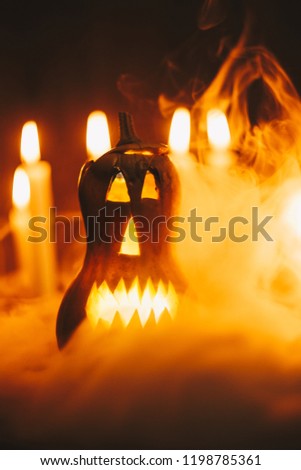 Jack-o-lantern in smoke among burning candles and apples. Halloween holiday, national, tradition. atmospheric photo. harvest day, autumn