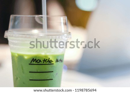 Iced matcha green tea latte on table with women working in store.