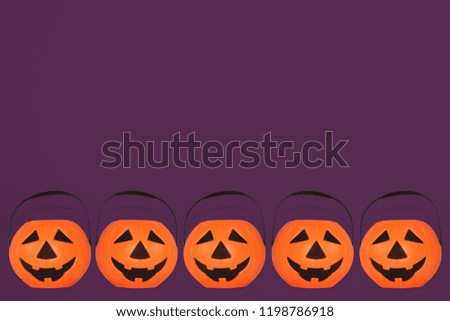 
Jack O' Lantern Halloween pumpkin pail on purple background. Orange plastic Trick Or Treat candy bucket made from resin with handle.