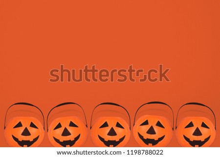 
Jack O' Lantern Halloween pumpkin pail on orange background. Orange plastic Trick Or Treat candy bucket made from resin with handle.