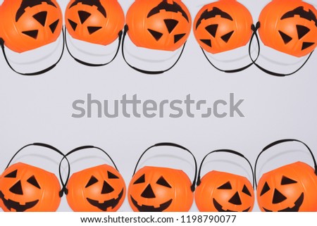 
Jack O' Lantern Halloween pumpkin pail on grey background. Orange plastic Trick Or Treat candy bucket made from resin with handle.