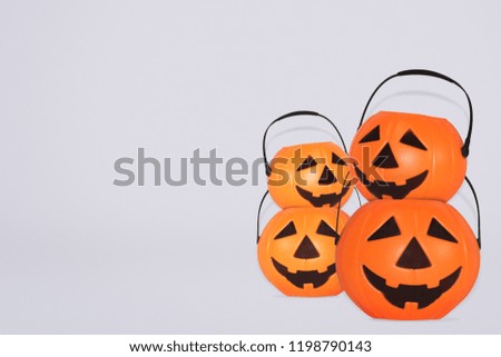 
Jack O' Lantern Halloween pumpkin pail on grey background. Orange plastic Trick Or Treat candy bucket made from resin with handle.