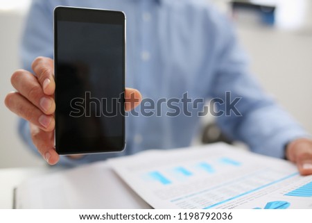 A businessman holds a new smartphone in his hand The mobile application market shows a display you can insert your image for advertising or financial statistics
