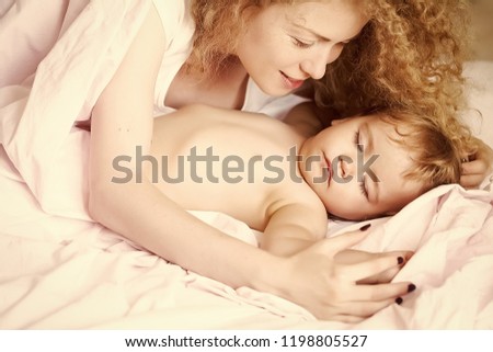 Closeup of young beautiful mother with light blonde curly hair sleeping with little tiny cute male lovely baby indoor in bed with white linen lying close to each other, horizontal picture