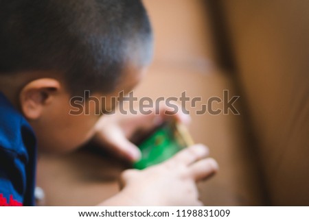Abstract blur unidentified little boy play mobile phone