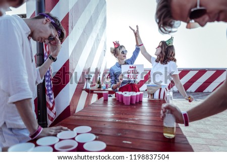Female power. Negative delighted man bowing head while leaning on table