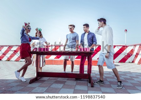 Express emotions. Attentive males looking at their friends while standing together near table