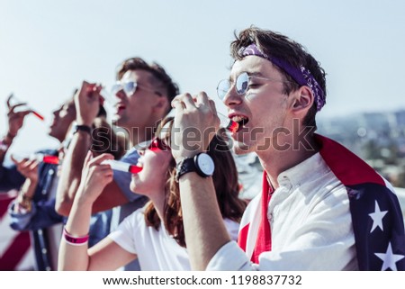 On style. Group of young people that standing in line and drinking red cocktail