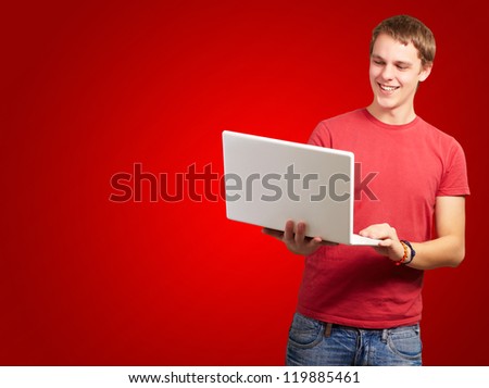 Happy man using laptop isolated on red background