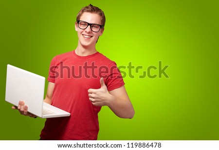 Man holding laptop with thumbs up isolated on green background