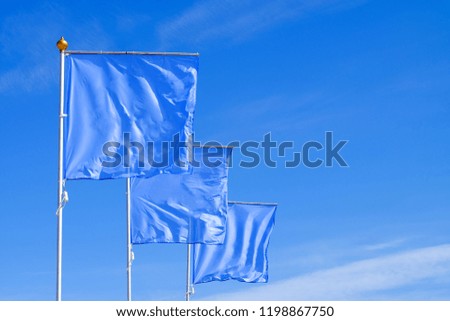 Blue flags waving in the wind against the cloudless sky. Perfect layout to add any logo, symbol or sign