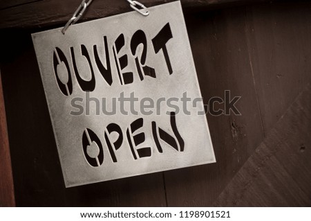 closeup of metallic panel with text "Open - Ouvert" in french and in english on wooden door