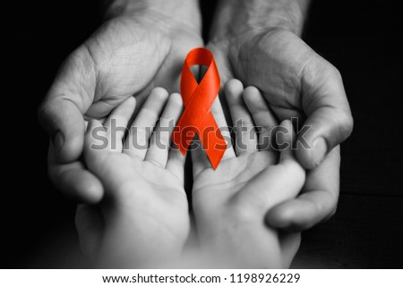 child with AID red ribbon on a dark background. the boy holds the symbol of the fight against HIV, AIDS and cancer. concept of helping those in need.black and white.