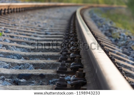 Close-up of the screws on the rail for the train. The sleepers and the two tracks in the distance span into each other. Royalty-Free Stock Photo #1198943233
