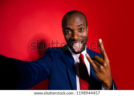 Job work worker chic confident cool crazy man in style deep blue blazer formalwear take selfie on front camera modern gadget smartphone show rock n roll sign isolated on red bright background