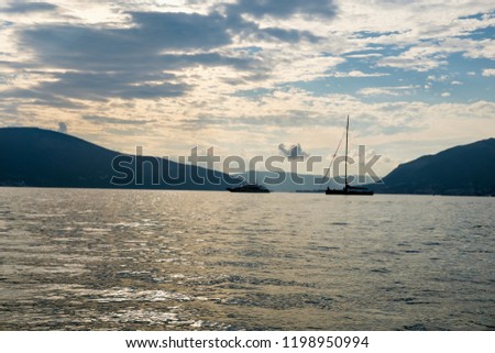 Sailboat in the sea in the evening sunlight over beautiful big mountains background, luxury summer adventure, active vacation in Tivat, Montenegro