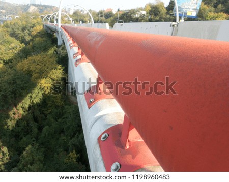 detail of a huge round red railing on a concrete bridge