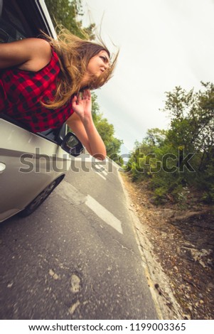 Woman having fun with her head out of the car on a windy day