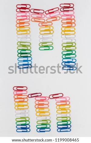 Alphabet M made from color paper clips on white background. uppercase and lowercase, rainbow pattern, top view