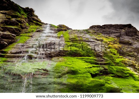 Beautiful waterfall over mossy stones in the Cove of Tintagel in Cornwall