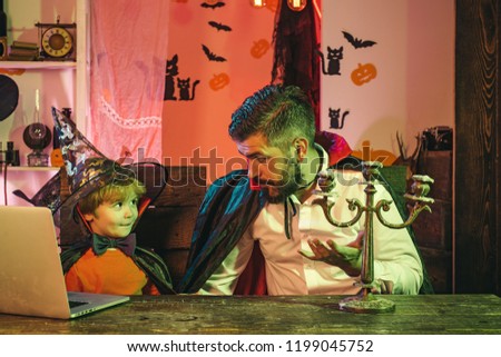 Happy family on Halloween. Father and son are shopping online. The family is sitting at the table and planning an autumn break. Halloween Holidays. Male conversation