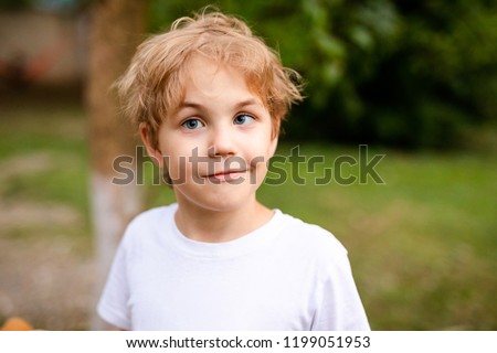 Blonde smiling boy with strabismus in warm park Royalty-Free Stock Photo #1199051953