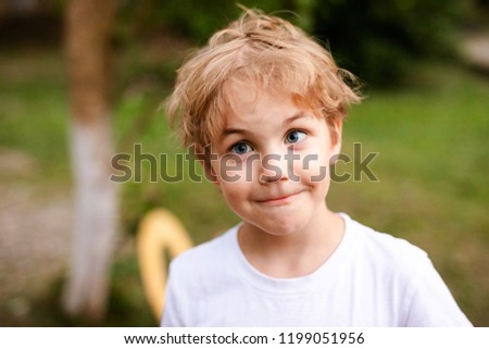 Blonde smiling boy with strabismus in warm park Royalty-Free Stock Photo #1199051956