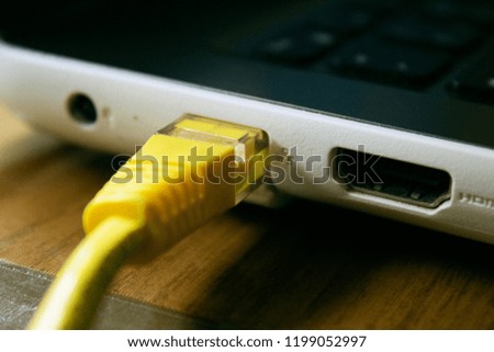 Yellow twisted network cable connected to laptop, closeup.