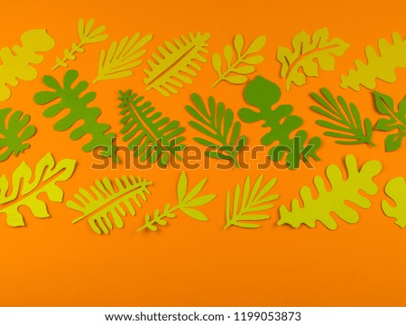 Green leaves made from paper on orange background. Autumn leaf fall. Favorite hobby handicraft.