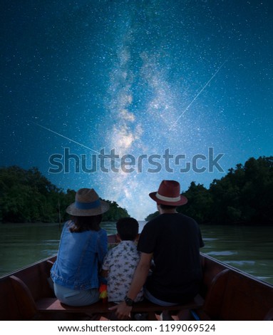 Asian family silhouette Take a boat ride to enjoy the beauty of nature at night. Among the Milky Way galaxies During summer holidays. Long exposure, with grain.